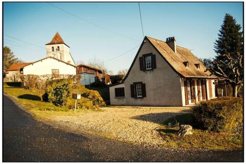 a large white house with a church in the background at Maison familiale de campagne in Brantôme