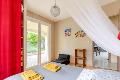 ein Schlafzimmer mit einem Bett und einem Stuhl und einem Fenster in der Unterkunft Agréable logement avec piscine entre mer et vignes in Maureilhan-et-Raméjan