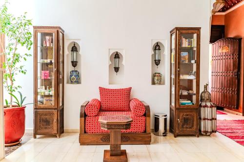 a living room with a red chair and a table at Riad Mandana & Spa in Marrakech