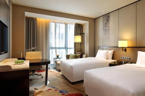 a hotel room with two beds and a desk at Anyang Wanda Realm Hotel in Anyang