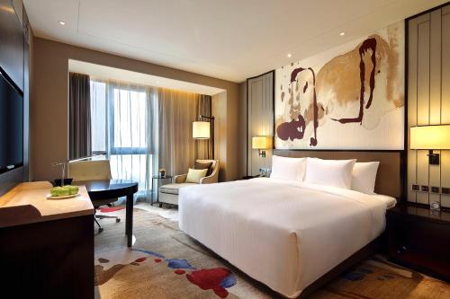 a bedroom with a large white bed and a desk at Anyang Wanda Realm Hotel in Anyang