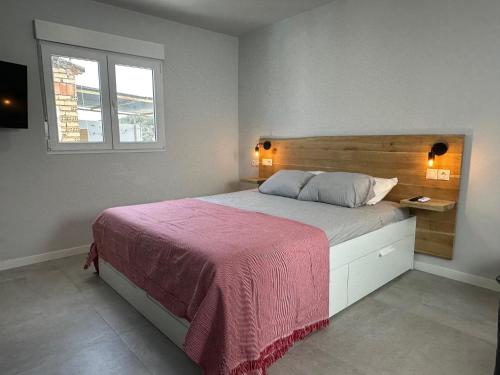 a bedroom with a bed with a pink blanket and a window at Casa Amapola in Setenil