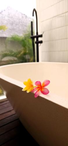 una bañera con flores al lado. en Swaha at Canggu Villa 1, en Canggu