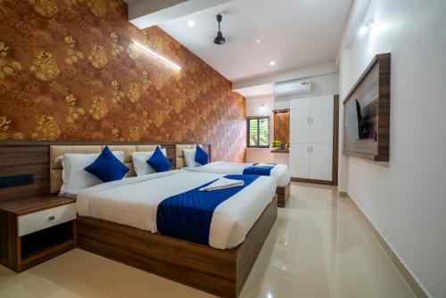 a bedroom with a large bed with blue pillows at Amala Arcade AC Rooms in Trichūr