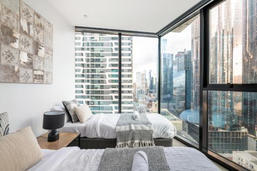 two beds in a room with a large window at Mega Style Apartments Light House in Melbourne