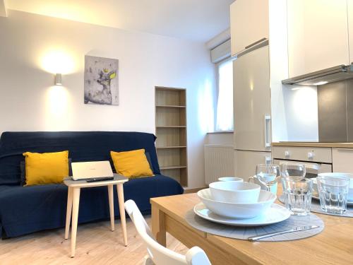 un salon avec un canapé bleu et une table dans l'établissement Appart'Village Le Creusot centre - Parking facile - Bus gare TGV 17 min, au Creusot