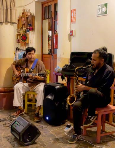 two men sitting in a room playing instruments at Hostel Cultural Pata y Perro in Tarija