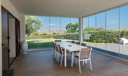 a dining room with a table and chairs and large windows at VENTO DI GISIRA in Brucoli