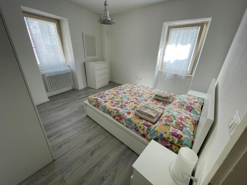 a small bedroom with a bed and two windows at Casi di Lisi, la luce sulla piazza e sulle montagne in Lisignago