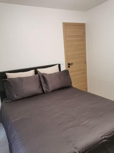 - un lit avec des draps et des oreillers gris dans une chambre dans l'établissement Appartement centre ville rdc, à Évreux