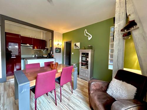 une cuisine et une salle à manger avec une table en bois et des chaises roses dans l'établissement Cosy T2 au Mont Dore Sauna privé et vue montagne proche thermes, à Le Mont-Dore