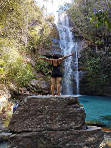 a woman standing on a rock in front of a waterfall at ECOS GAIA Casa Céu in Cavalcante