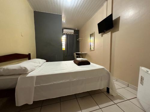 a bedroom with a white bed and a television at Xenius Hotel Macapá in Macapá