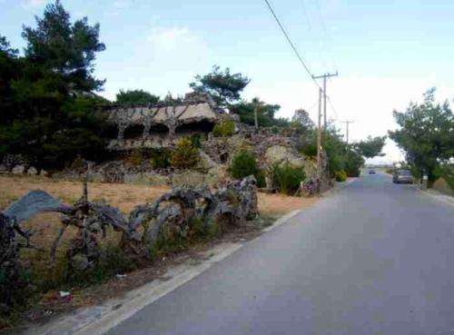 an empty road with a stone building on the side of the road at Rooms the other side of the island by Patitiri in Saterlí