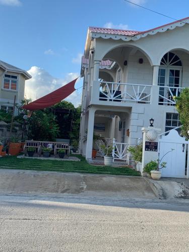 a white house with a table and a fence at Sea Shells Villa in Christ Church