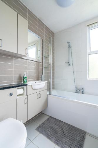 a white bathroom with a tub and a sink and a toilet at Ingham - Accessible Bungalow in Newlyn