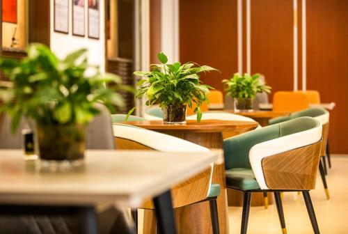 a restaurant with tables and chairs and potted plants at Zhong An Hotel Beijing Former Residence of Journalist Edgar Snow -Free laundry service,Free freshly ground coffee,Provide tourism and ticketing service ,English service ,Near Tian'AnMen Forbidden City,Wangfujing walking street in Beijing