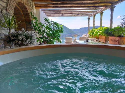 a hot tub on a balcony with a view of the mountains at Il Monsignore - Finnish WoodenJacuzzi and Stunning Lake Views in Cernobbio
