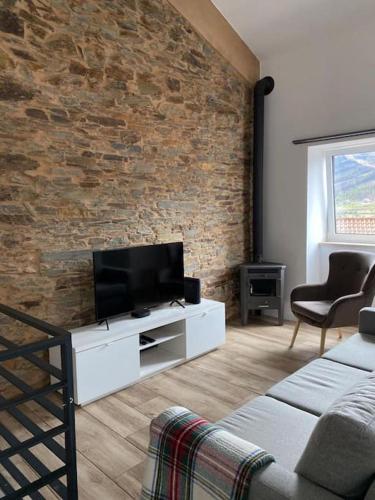 a living room with a tv and a brick wall at Lugar da Borralheira in Verdelhos