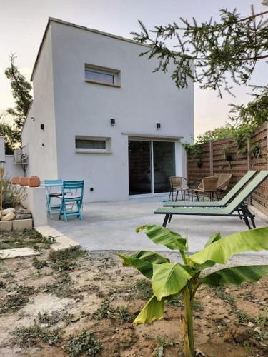 a white house with chairs and a patio at Havre de paix ressourçant in Mallemoisson