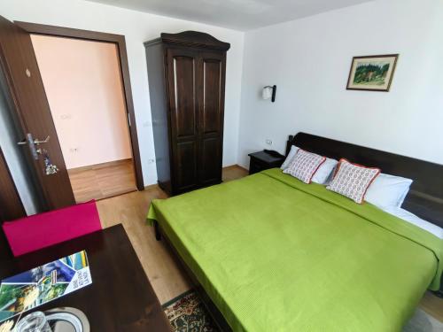 a bedroom with a green bed and a door at Pensiunea Pastravaria Vistisoara in Vistisoara