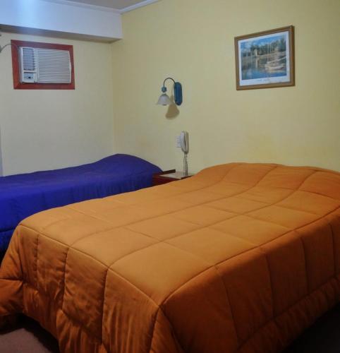 a bedroom with two beds and a phone on the wall at HSJ Balcarce in Balcarce