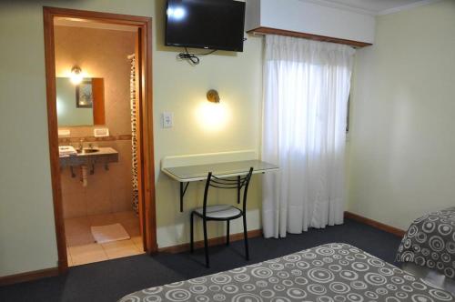 a room with a bed and a table and a bathroom at HSJ Balcarce in Balcarce