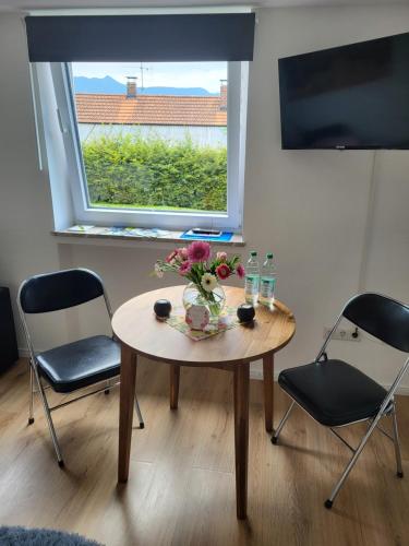 a table with flowers on it in a room with a window at Andreas Zugspitzblick in Murnau am Staffelsee