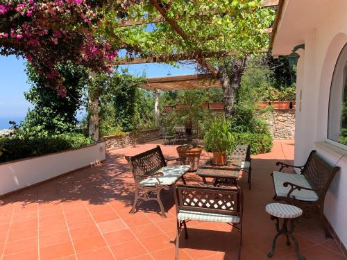 a patio with chairs and tables and a pergola at Casa Blu in Anacapri