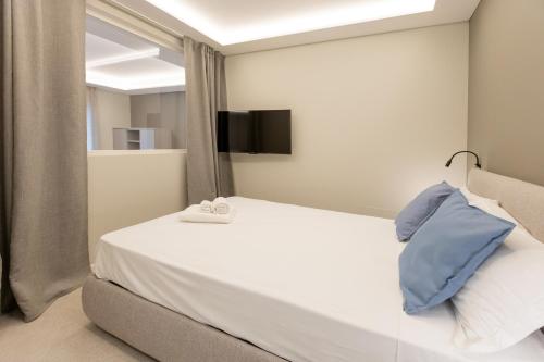 a bedroom with a white bed with a tv on the wall at Teatro Romano Exclusive Suites in Trieste