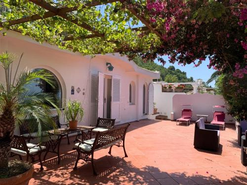 a patio with chairs and tables and a tree at Casa Blu in Anacapri