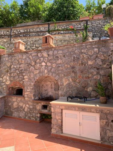 an outdoor kitchen with a stone wall and an oven at Casa Blu in Anacapri