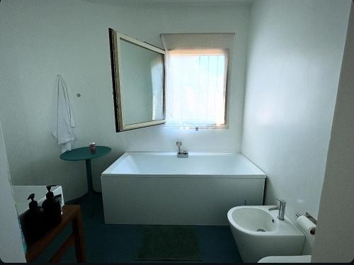 a bathroom with a tub and a toilet and a sink at Villa Velta Sea Sunset in Porto Santo Stefano
