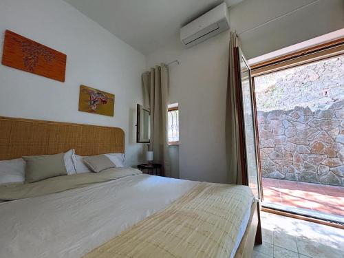 a bedroom with a bed and a large window at Villa Velta Sea Sunset in Porto Santo Stefano