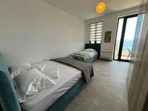 two beds in a bedroom with a view of the ocean at Dioneida Apartments in Sarandë