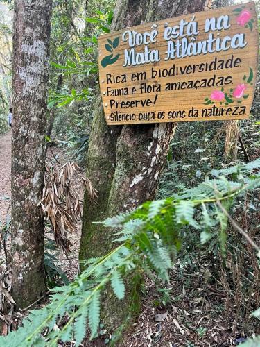 a sign on the side of a tree in a forest at Pousada Sitio da Terra e Arte in São Roque