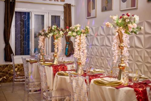 a dining room with tables with white and pink flowers at NINJA HOUSE Studio chic Le Turquois Doré in Yaoundé
