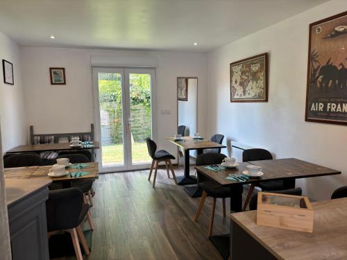 a restaurant with tables and chairs and a window at La villa Émeraude in Nernier