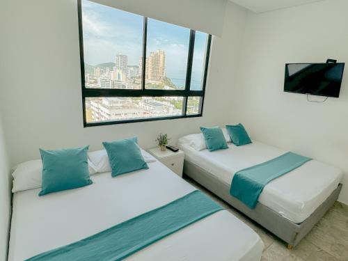 two beds in a room with a window at Apartasuites VITA 945 RODADERO - By Bedviajes in Santa Marta