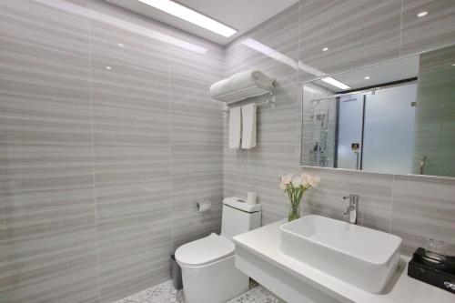 a bathroom with a sink and a toilet and a mirror at 深圳市千吉精致酒店 in Shenzhen