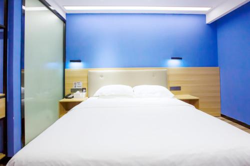 a bedroom with a large white bed with a blue wall at 深圳市千吉精致酒店 in Shenzhen