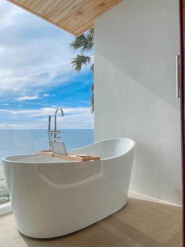 a bath tub with a sink in front of a window at เดอะซีน คาบาน่า บีช รีสอร์ท ขนอม The Scene Cabana Beach Resort Khanom in Ban Plau