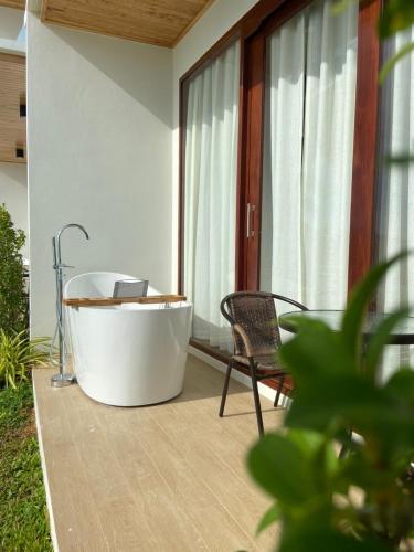 a bath tub sitting on a patio with a chair at เดอะซีน คาบาน่า บีช รีสอร์ท ขนอม The Scene Cabana Beach Resort Khanom in Ban Plau