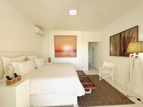 a bedroom with a large white bed and a chair at Pe na Areia Boutique Hotel in Japaratinga