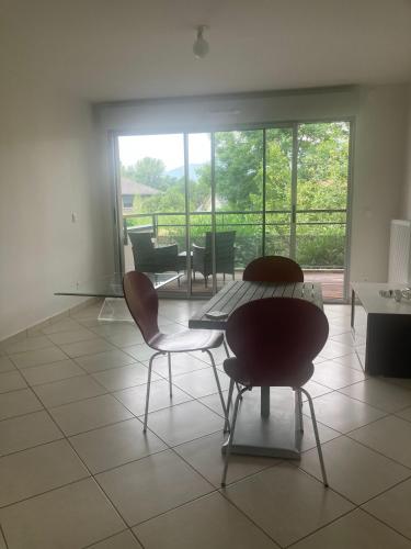 Cette chambre dispose d'une table et de chaises et offre une vue sur le patio. dans l'établissement Résidence Five luxe wi-fi, à Ornex