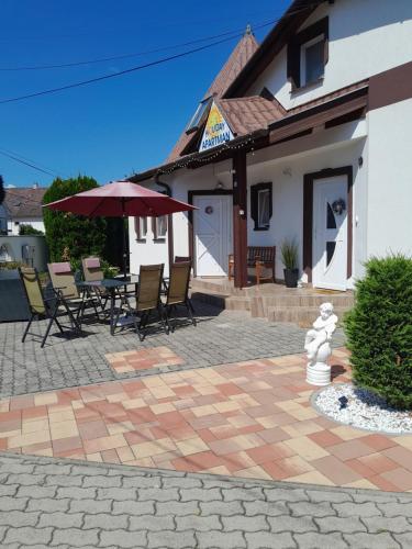 a patio with chairs and a table with an umbrella at Holiday Apartman in Bük