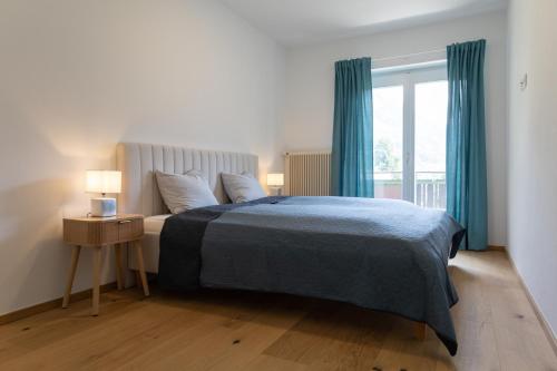 a bedroom with a bed with a blue blanket and a window at Top Four See- & Bergblickapartment - 250m vom Seeufer in Döbriach
