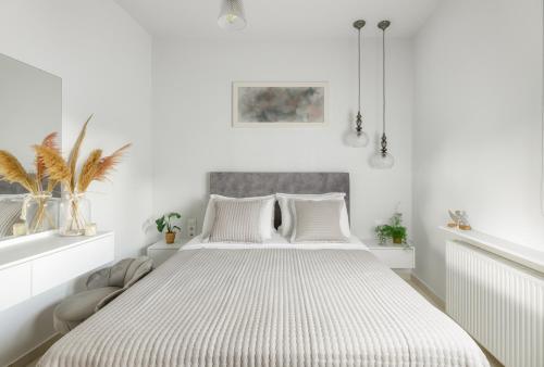 a white bedroom with a large bed with white sheets at Historical Old Town Luxury Apartment in Ierápetra