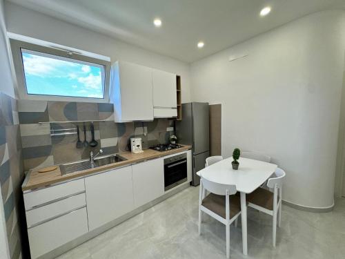 a kitchen with white cabinets and a table and a window at Nicola's Apartments in Santa Maria La Carità