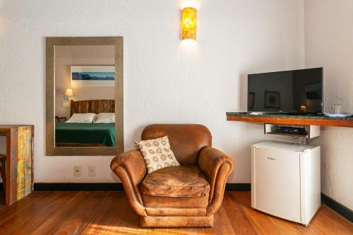 a living room with a chair and a television at Pousada Casa da Lagoa in Florianópolis